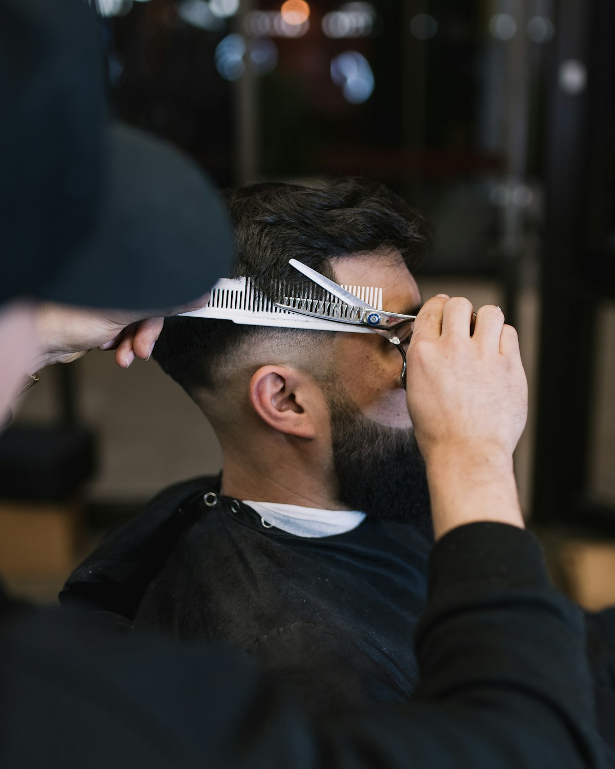 Konturschnitt mit Effilierschere und Kamm, Barbershop im Hintergrund unscharf